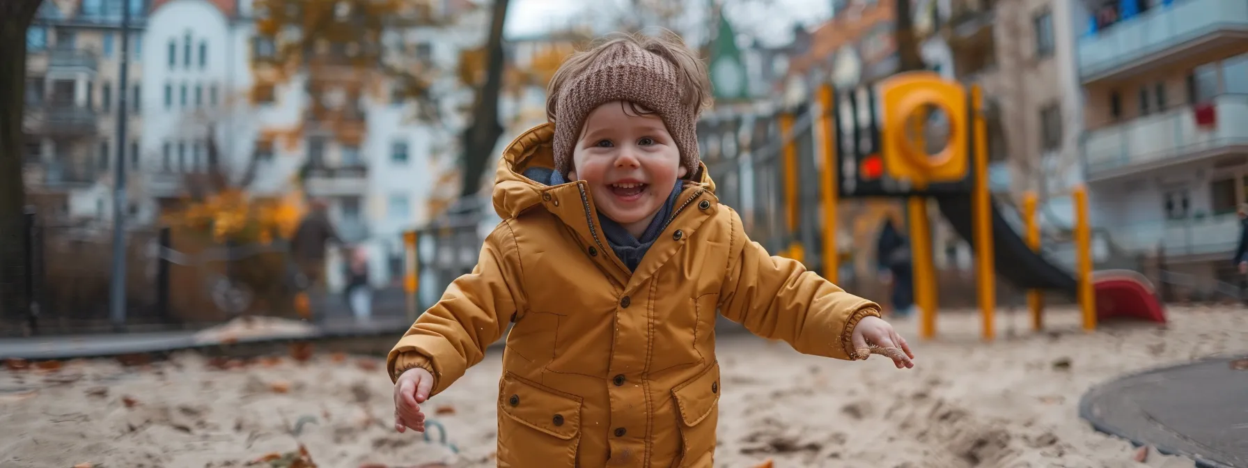 ein glückliches kind rennt lachend über einen spielplatz vor einem familienfreundlichen hotel in berlin.